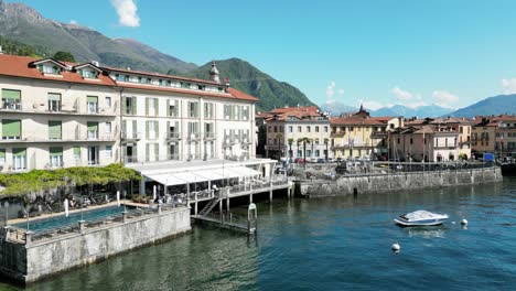 waterfront view of menaggio with historic buildings, moored boats, and alpine backdrop. menaggio, lago di como, italy