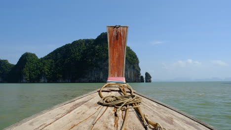 Shot-of-the-front-of-a-modest-wooden-boat-sailing-through-Thailand's-tropical-waters