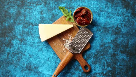 Grated-parmesan-cheese-and-metal-classic-grater-placed-on-wooden-cutting-board