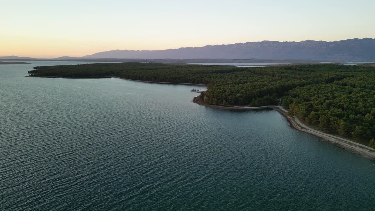 la vista desde arriba sobre el bosque de pinos verdes y la montaña velebit en la luz del atardecer en vrsi mulo, región de zadar, croacia