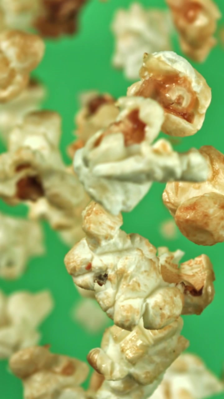 Chicchi di popcorn deliziosi che cadono al rallentatore su schermo verde