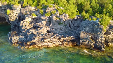 the pine trees covered rocky banks with the deep, crystal clear waters of lake huron