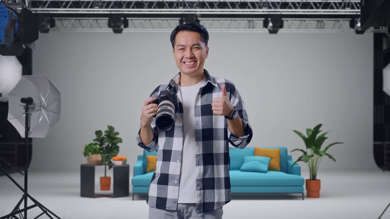 Fotografo sorridente che fa il pollice in su in uno studio.