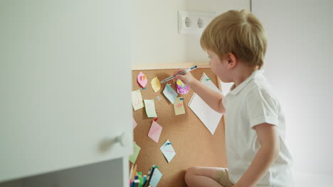 blond preschooler draws with ball-pen on piece of paper