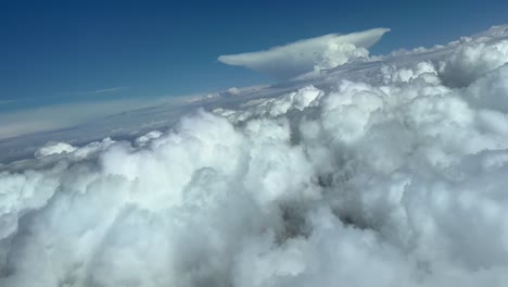 Impresionante-Vista-Desde-La-Cabina-De-Un-Jet-Durante-Un-Giro-A-La-Derecha-Para-Evitar-El-Mal-Tiempo-Por-Delante,-En-Un-Cielo-Lleno-De-Cúmulos-Y-Una-Enorme-Forma-De-Yunque-Cumuloninbus-En-La-Parte-Posterior