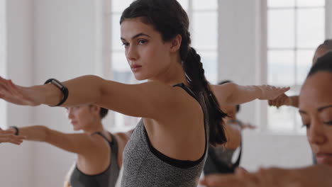 healthy caucasian yoga woman practicing warrior pose meditation with group of multiracial women enjoying fitness lifestyle exercising flexible body in workout studio