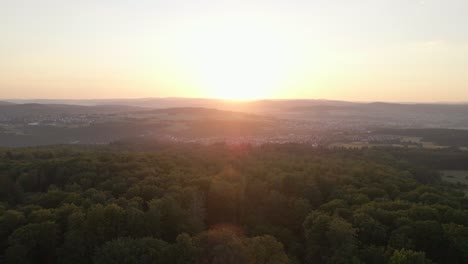 Sunset-drone-flight-over-forests-and-mountains-with-a-village-in-the-valley