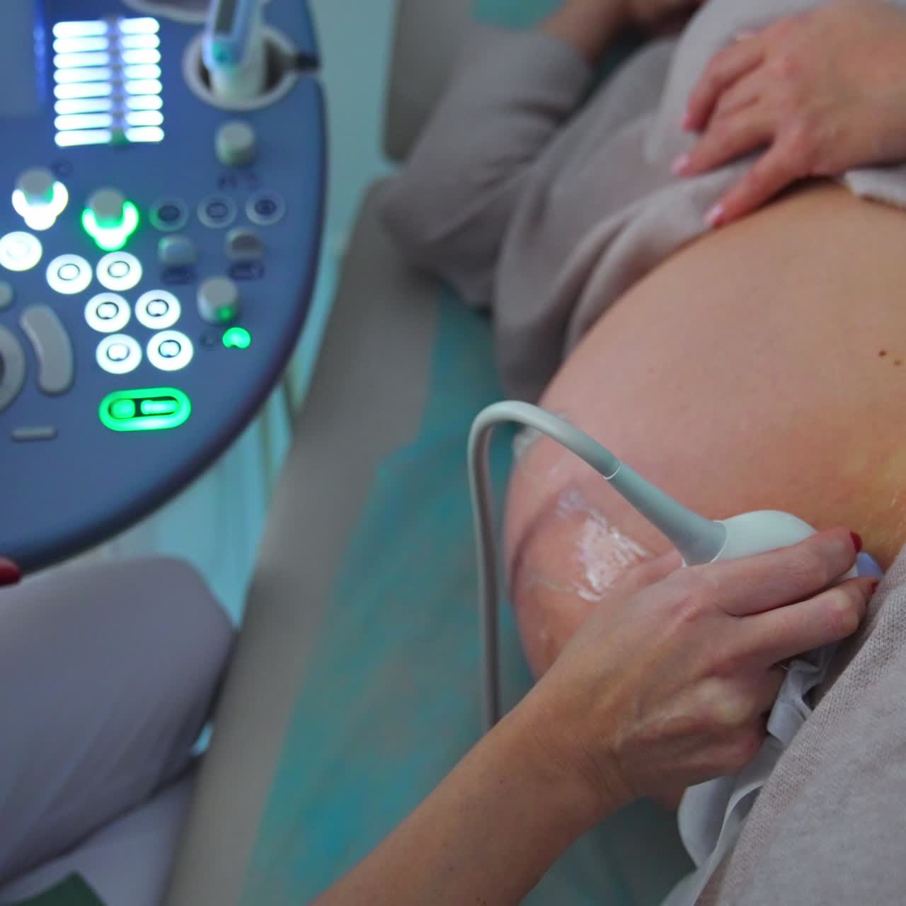 Una donna incinta è sdraiata su un fianco e il medico esegue una diagnostica ecografica. L'ostetrico muove il dispositivo a ultrasuoni sull'addome della paziente.
