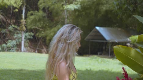 blonde hair girl admiring a flower at a ranch on the caribbean island of trinidad