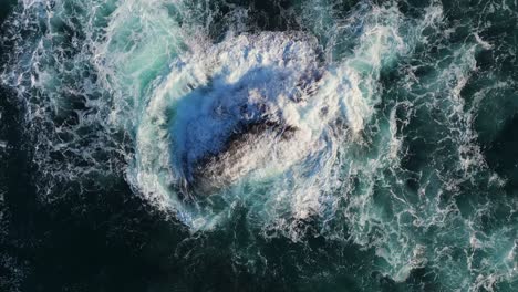 rough waves hitting outcrop near mera beach in a coruna, galicia spain. aerial slow motion shot