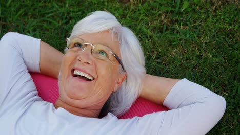 Senior-woman-lying-on-exercise-mat-in-garden-4k
