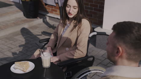 happy disabled girl in wheelchair talking with a friend in a bar terrace