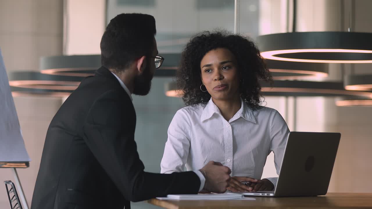 Young middle eastern ethnicity businessman shaking hands with african businesswoman.