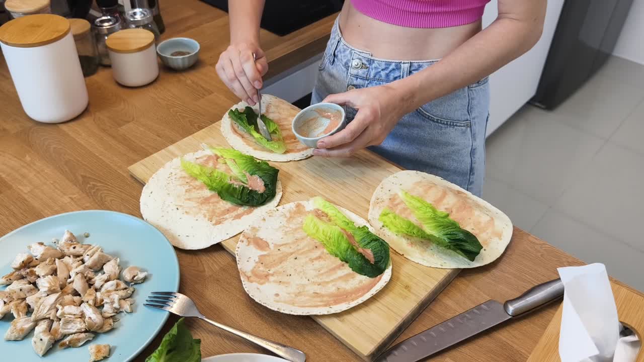 mujer preparando envolturas de ensalada de pollo en una cocina