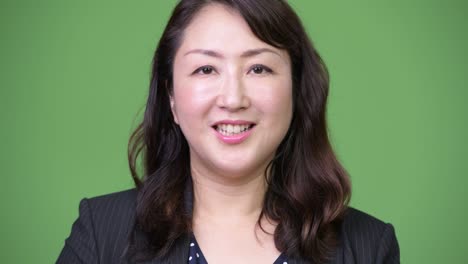 녹색 배경에 성숙한 아름다운 아시아 사업가
