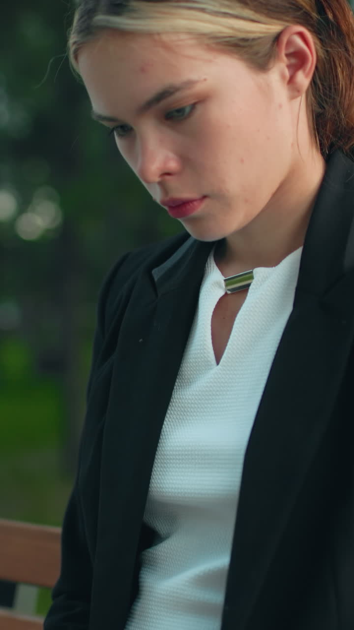 Remote worker seated in calm park on wooden bench typing on laptop with coffee cup by her side focused on task surrounded by peaceful greenery and trees