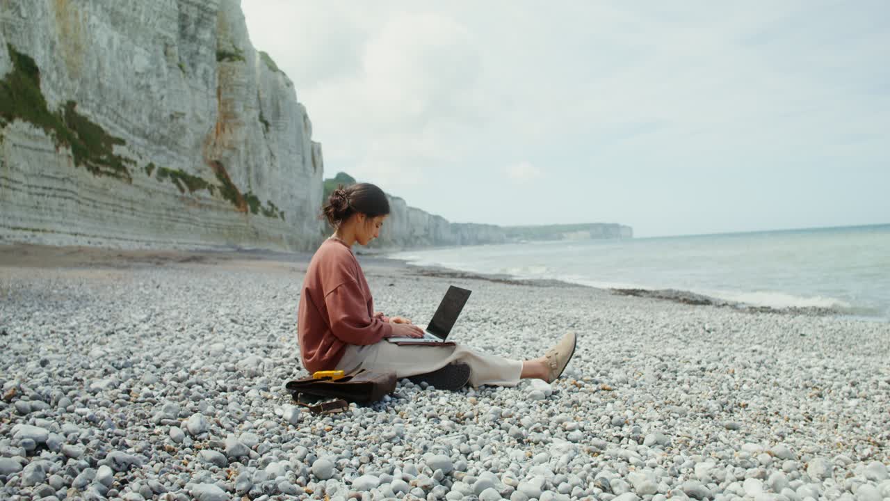 Donna che lavora al laptop in spiaggia