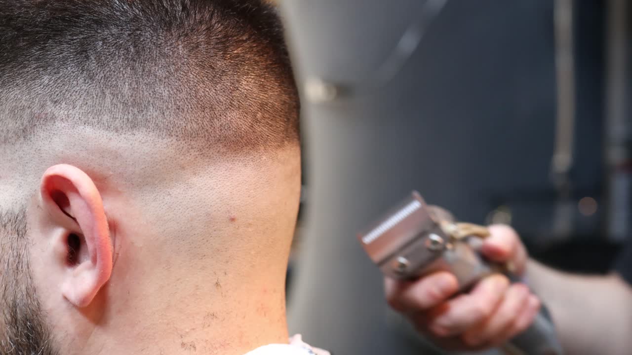 fotografía de cerca de un barbero recortando el cabello de un cliente masculino con cortadoras de cabello mientras trabajaba en una barbería