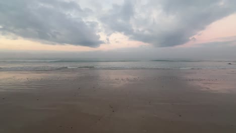 Ruhige-Und-Heitere-Aussicht-Auf-Die-Wellen,-Die-Ans-Ufer-Krachen,-Mit-Wolken-Am-Horizont,-Die-Die-Unberührte-Schönheit-Der-Natur-Verkörpern