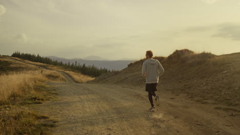hombre activo corriendo en las montañas. corredor masculino entrenando en la superficie del suelo al aire libre