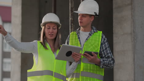 construction worker and engineer talking at construction site site. workers in helmets at building area. portrait of construction engineers working on building site. concept of modern construction