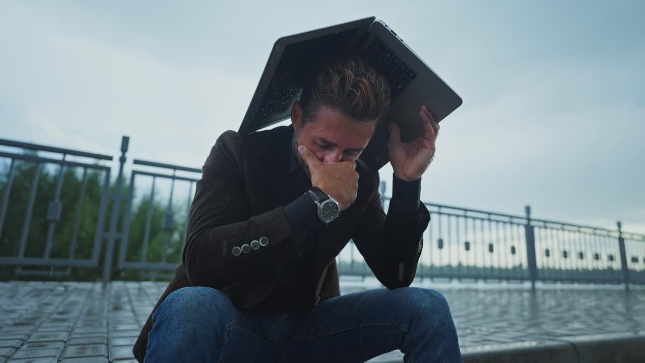 Stressed Businessman in Rain with Laptop