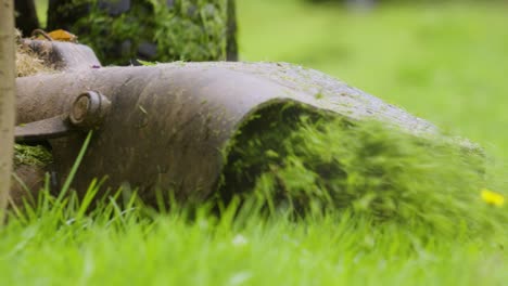 Bodenansicht-Eines-Rückwärtsfahrenden-Aufsitzrasenmähers-Mit-Grünem-Grasschnitt,-Der-In-Zeitlupe-4k-In-Richtung-Kamera-Ausgeworfen-Wird