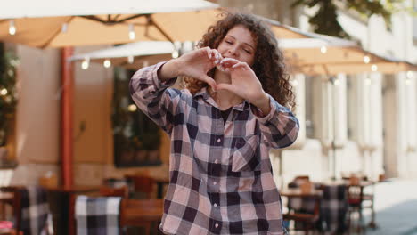 young woman makes symbol of love showing heart sign to camera express romantic positive feelings