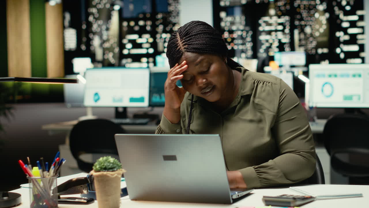 African american woman realizing she works alone late at night in the office
