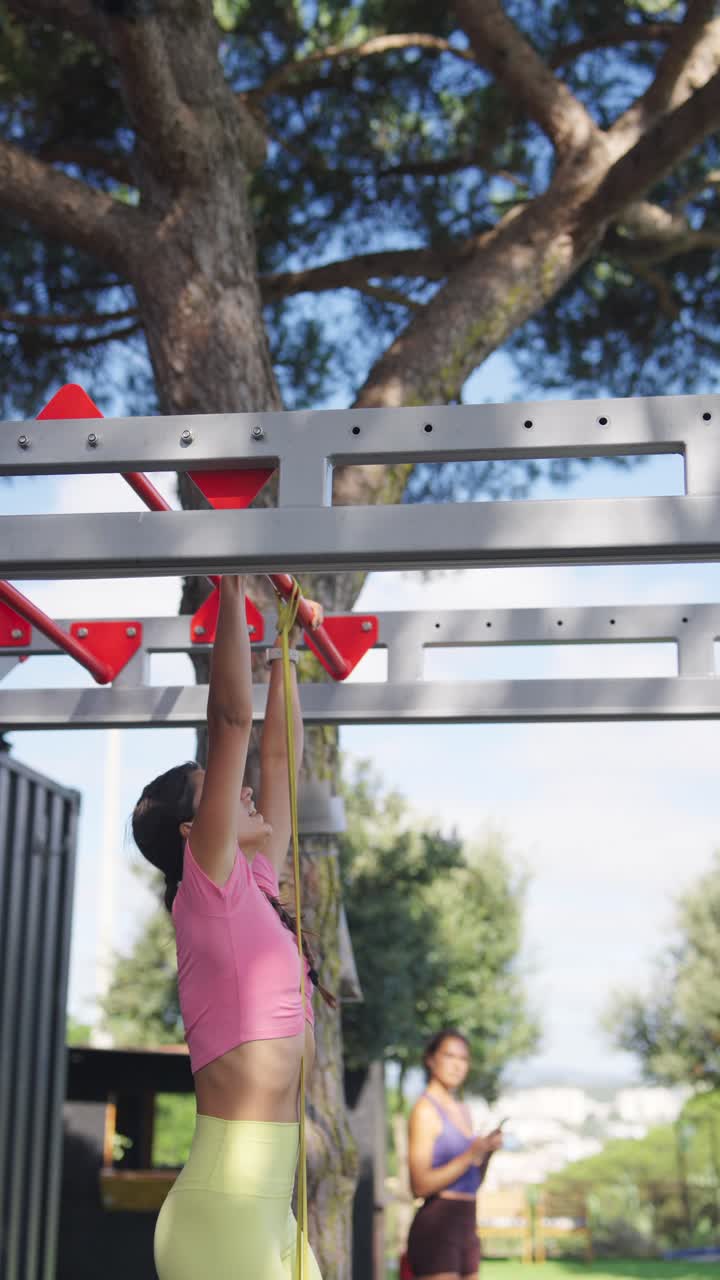 Woman doing pull-ups with resistance band at an outdoor gym