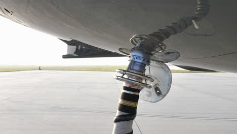 air start unit discharge air hose attached to aircraft underbelly, starting jet engine on the airfield