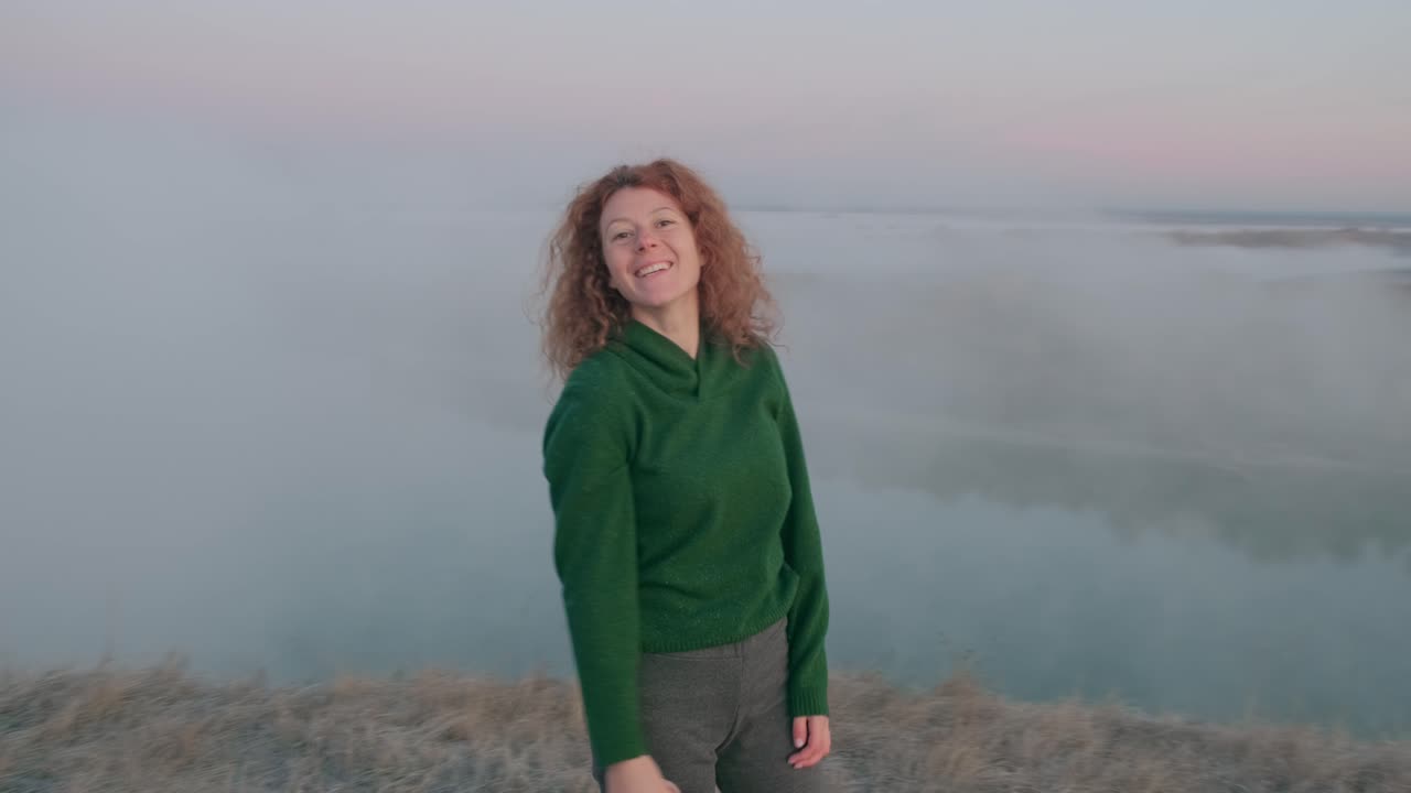 Lächelnde Frau bei Sonnenaufgang über nebligem Fluss