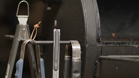 tongs-being-placed-on-open-BBQ-pit-smoker-and-lid-closes-in-slow-motion