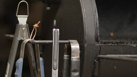 tongs being placed on open bbq pit smoker and lid closes in slow motion