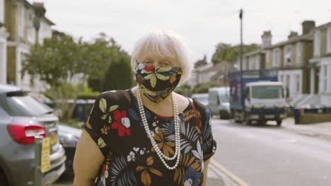 elderly woman wearing a face mask with matching dress looking at the camera moving head