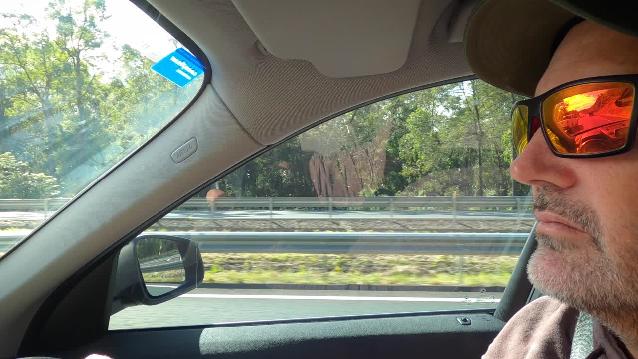 추월당하는 고속도로에서 순항하는 선글라스를 쓴 차분한 남자