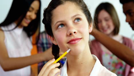 Thoughtful-schoolgirl-holding-pencil-in-laboratory