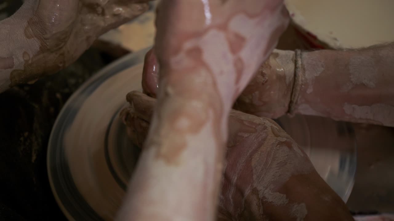 un alfarero enseña a una mujer a hacer platos de arcilla. un hombre toma las manos de una mujer