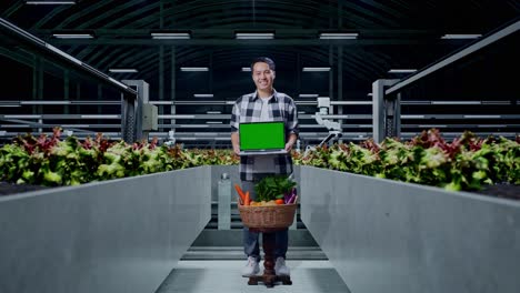 smiling man with laptop in modern greenhouse farm