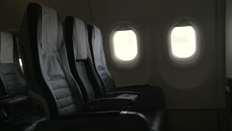 se ve la decoración interior del avión - sillas de cuero negro y dos persianas