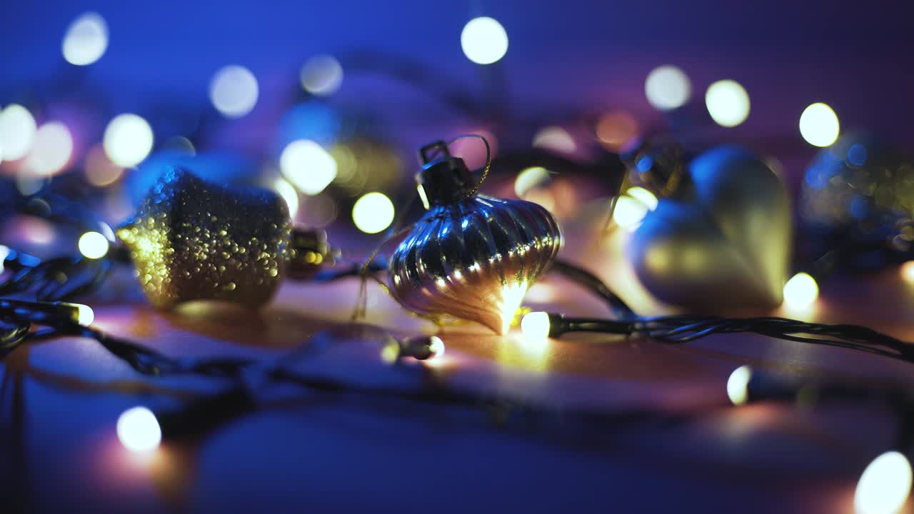 Close-up shot of garland with golden lights and christmas toys on color background. Christmas concept. Home decor. Beautiful bokeh