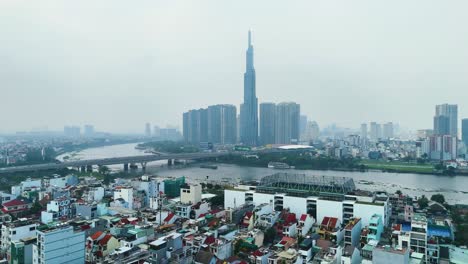 Aerial: Landmark 81 supertall skyscraper during the day with pollution in Ho Chi Minh City, Vietnam, establishing drone shot