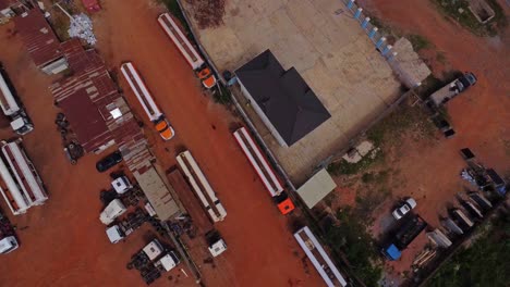 top down aerial of fuel trucks parked alongside industrial buildings in nigeria, africa