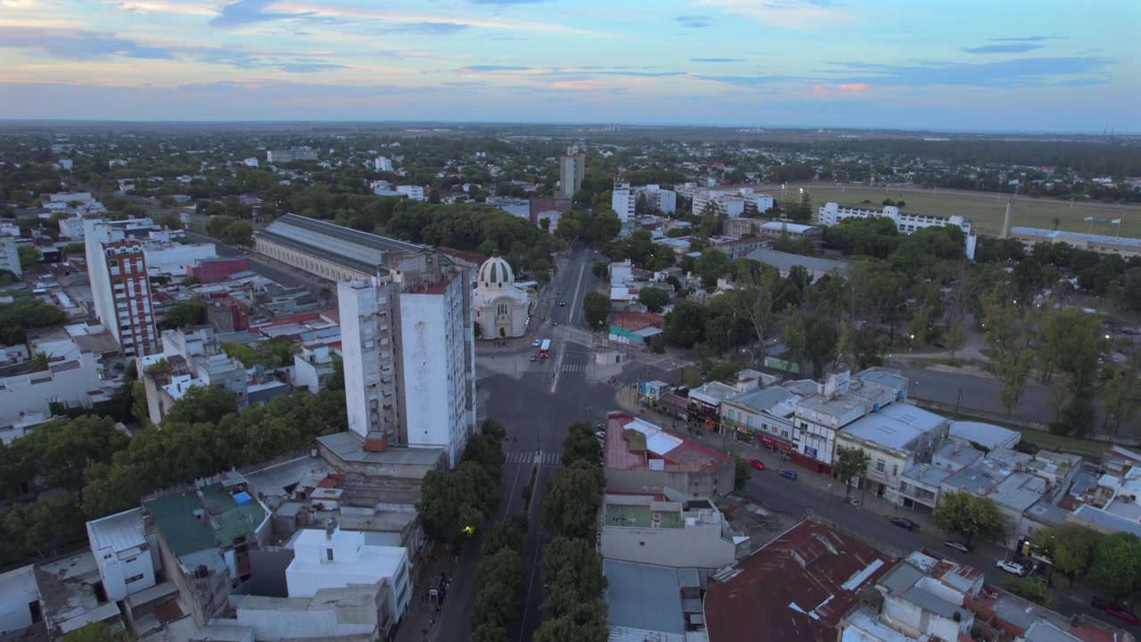 Vista aérea con dron 4K de La Plata, Buenos Aires, Argentina al atardecer. Horizonte urbano, edificios y calles iluminados por la cálida luz vespertina en toda la ciudad