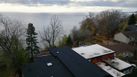 an overhead drone dolly over a residential neighborhood with sleek modern homes surrounded by trees calm peaceful lake views at sunset