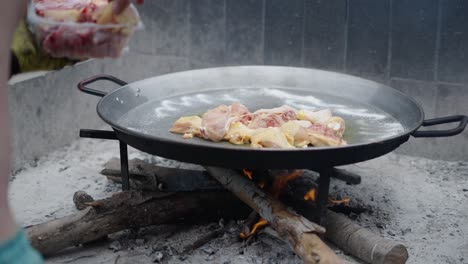 cooking chicken over an open fire in a large pan