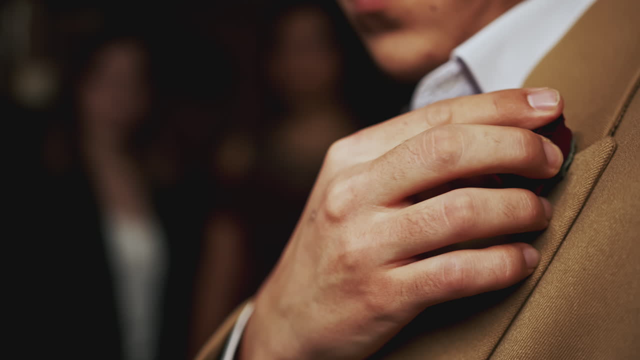 hombre ajustando un alfiler de rosa en una chaqueta de traje