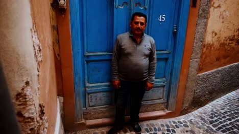 man in front of a blue door in a narrow alley