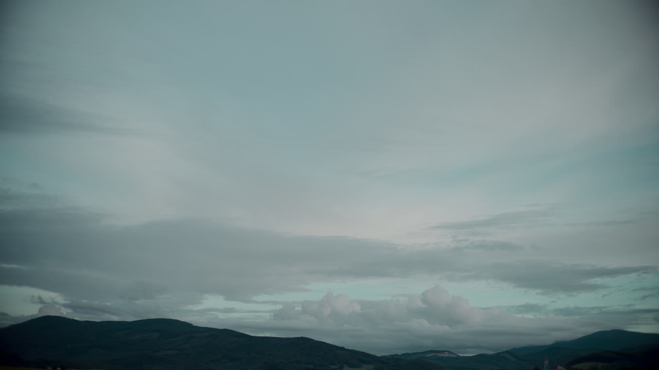해가 지는 동안 산 위에 움직이는 구름