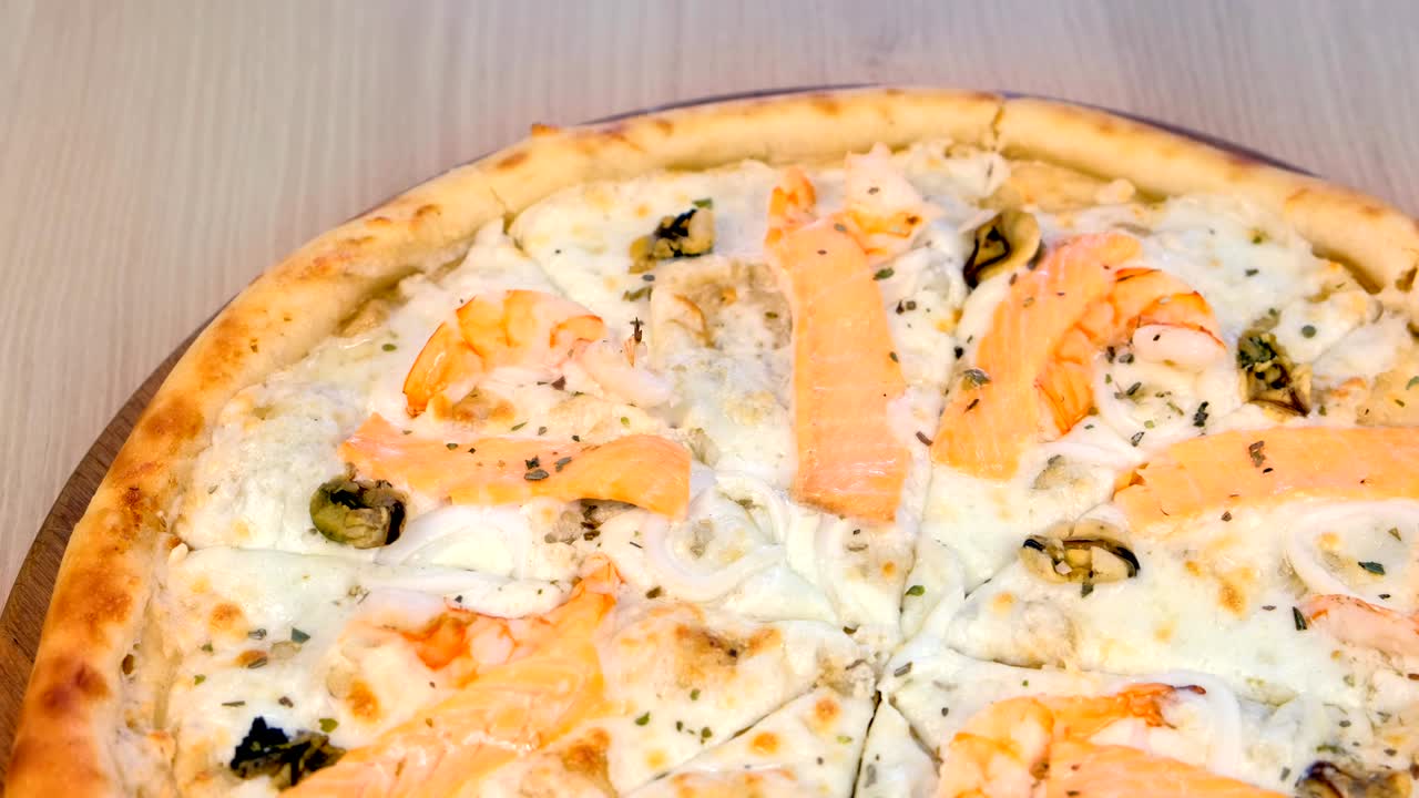 나무판 위에서 해산물과 치즈를 어낸 피자의 절반, 근접한 시각.